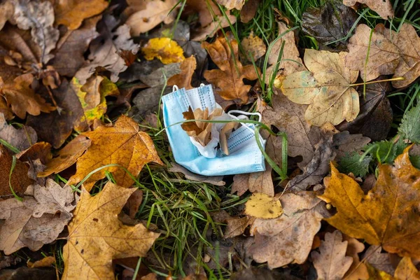 Yere Düşen Yapraklarla Kaplı Bir Cerrahi Maske — Stok fotoğraf