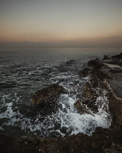 Вертикальный Снимок Морских Волн Разбивающихся Скалы Берегу Сумерках Закате — стоковое фото