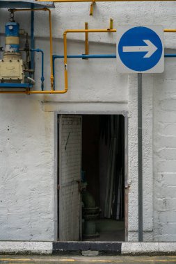 Tek yönlü trafiğin arka sokağında açık bir kapı, sağ mavi işareti, dikey çekim