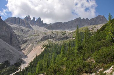 İtalya 'da mavi bulutlu gökyüzünün altında Dolomitlerin sıradağları ve otların güzel bir manzarası