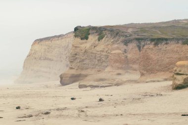 Kumlu bir sahil manzarası ve kayalık uçurumları