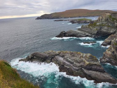 Gündüz vakti dağ oluşumları ve deniz kıyısına sahip manzaralı bir manzara.