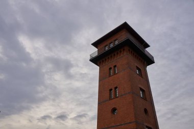 Bulutlu bir arkaplanda tuğla bir kule alçak açısı