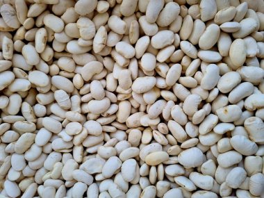 Güneşli bir günde açık hava pazarında kurutulmuş beyaz fasulyelerin yakın çekimi.