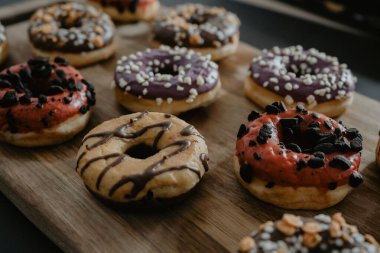 Çikolata ve vanilya kaplı, yakın plan bir fotoğraf, farklı dekore edilmiş, ahşap bir kesme tahtasında servis edilir.