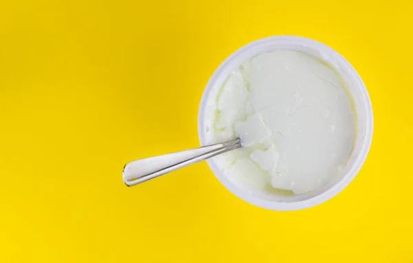 黄色背景下的酸奶汤匙的顶部视图 — 图库照片