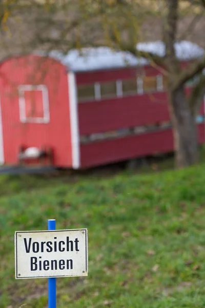 在德语中 一张红色蜂房的垂直照片 前面有一个标牌 上面写着 注意蜜蜂 — 图库照片