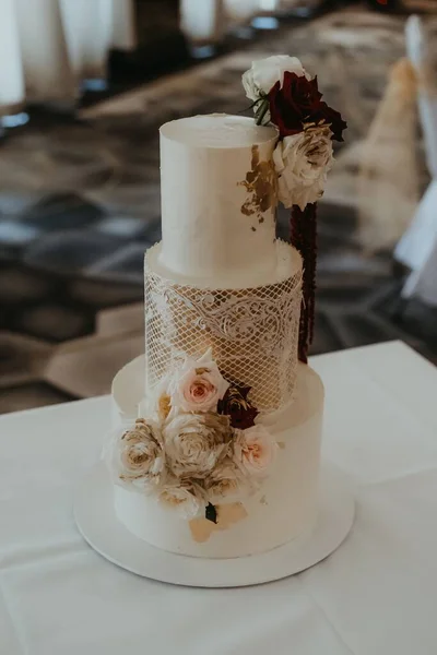 一种三层婚礼蛋糕 桌上有鲜花 — 图库照片