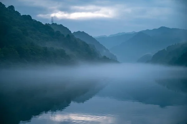 湖面上有反光 背景上有多雾的群山 — 图库照片
