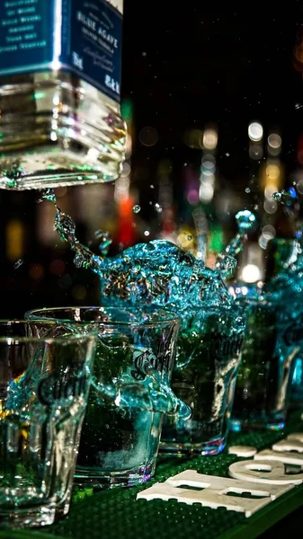 一张垂直拍摄的透明玻璃杯 晚上放在酒吧台上 里面放着伏特加 — 图库照片