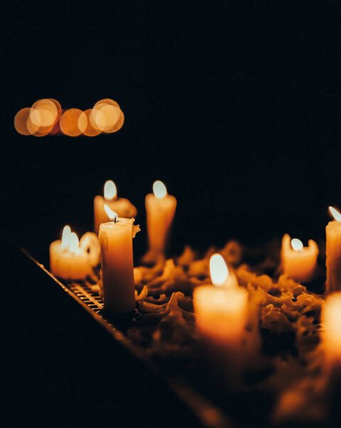 A vertical selective focus of several candles in a dark room