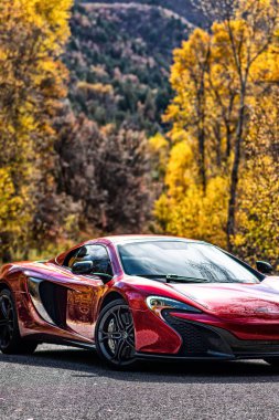 Kırmızı bir McLaren 650S Egzotik Araba Sonbahar ormanında Renkli ağaçlarla