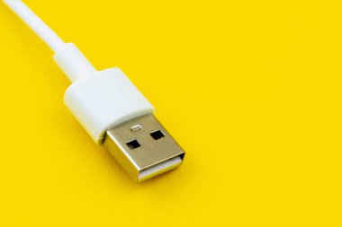 Sarı bir yüzey üzerinde beyaz bir USB kablosunun yakın plan görüntüsü.