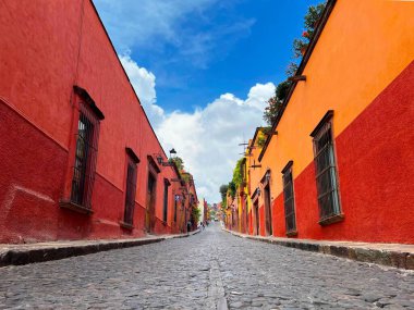 San Miguel de Allende, Meksika 'da mavi bulutlu gökyüzü altındaki eski geleneksel binalar arasında dar bir sokak.