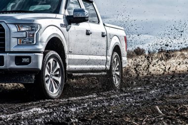 Ford F150 Gümüş Kamyon 4x4 SUV çamurda sürüyor.