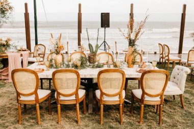 Düğün günü açık salonda ahşap sandalye ve dekorasyon manzarası.