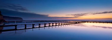 Kayalar ve köprülerle okyanusun üzerinde güzel bir gün batımı