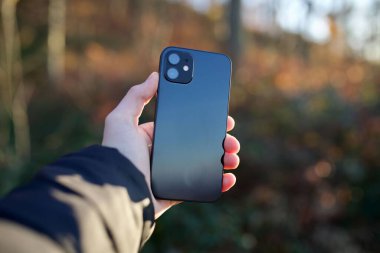 Doğa manzarasına karşı akıllı telefon tutan bir insan.