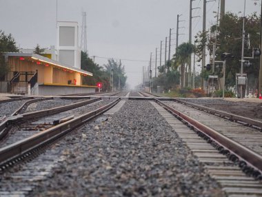 Tren raylarının zemin katındaki görüntüsü kasvetli gökyüzünün altındaki bir istasyonda.