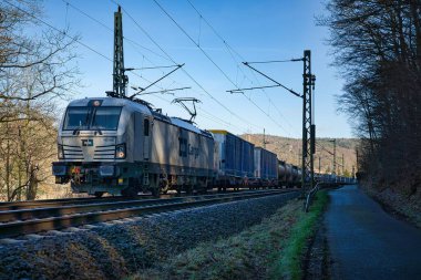 Ağaçlarla çevrili demiryolunda bir tren.