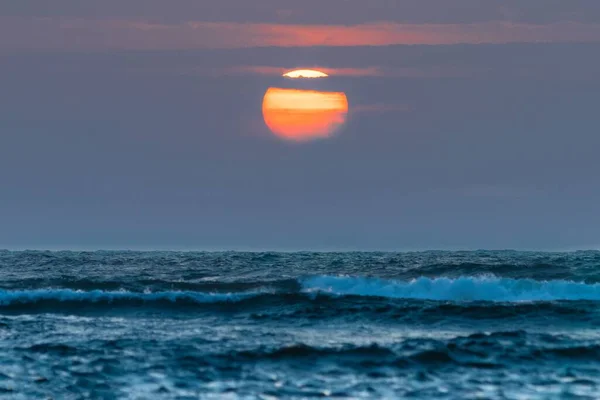 Maisemakuva Laskevasta Auringosta Pilvien Alla Myrskyisän Meren Aalloista — kuvapankkivalokuva