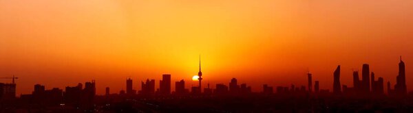 A silhouette shot of the beautiful city of Kuwait with a sunset in the background