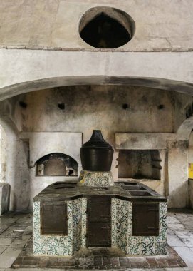 Certosa di Padula, Campania, İtalya 'da yemek pişirmek için eski ekipmanlara sahip bir mutfağın dikey görüntüsü.