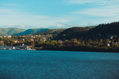 Arka planda ağaçlarla kaplı tepeleri olan güzel mavi su manzarası..