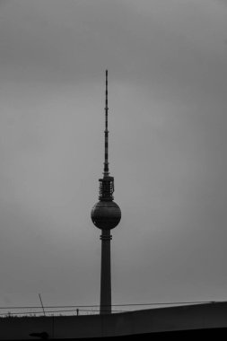 Berlin, Almanya 'daki Fernsehturm TV kulesinin dikey görüntüsü bulutlu gökyüzünün altında.