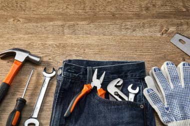 Turuncu ve siyah mekanik el aletleri seti ve ahşap arka planda kot pantolon.