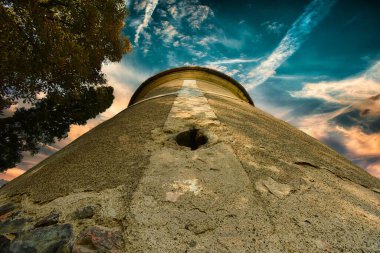 Gün batımında bulutlu mavi gökyüzünün altındaki bir kulenin alçak açılı görüntüsü..