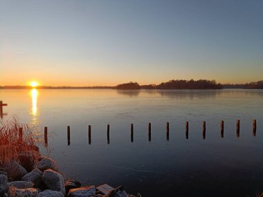 Gün batımında arka planda bir göl olan bir arazi.