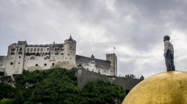 Yeşil ağaçlarla çevrili eski Hohensalzburg kalesine bakan bir adam, Salzburg
