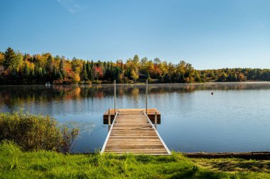 Bir rıhtım ve sonbahar ağaçları Fairburn, Quebec 'e yansıyor.