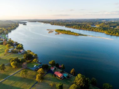 Güneşli bir günde ağaçlarla çevrili bir nehrin kuş bakışı görüntüsü.