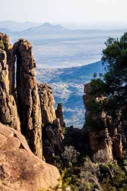 Arka planda dağ zirveleri olan kaya oluşumlarının dikey çekimi