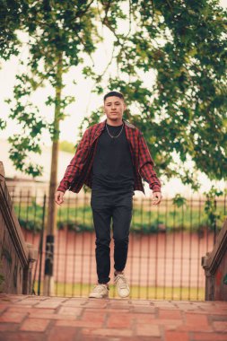 Çocuk parkında yürüyen yakışıklı bir gencin dikey görüntüsü.