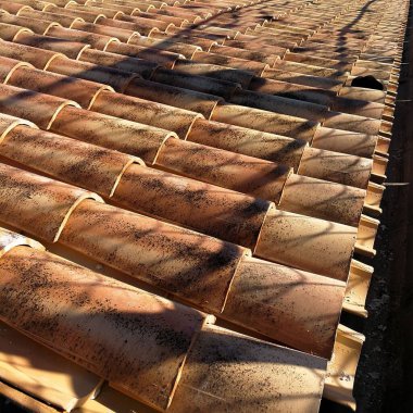 Güneşin gölgesi altında turuncu çatı fayanslarının yakın plan çekimi.