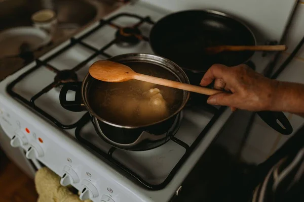 ストーブの上で醸造する木製のスプーンで手のクローズアップ — ストック写真