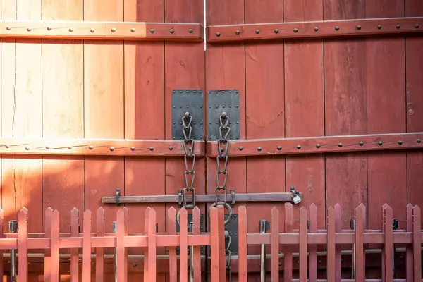 Nahaufnahme Einer Roten Holztür Mit Einem Zaun Davor Bei Tag — Stockfoto