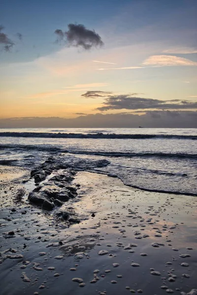 Вертикальный Снимок Пляжа Полного Скал Спокойным Морем Заднем Плане Вечером — стоковое фото