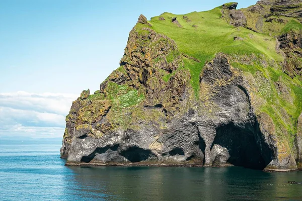 青い空に向かってアイスランドの海岸にある大きな緑の岩の風景 — ストック写真