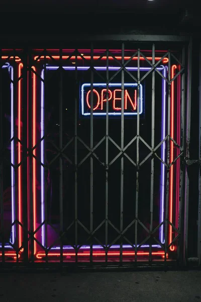 鉄の棒の後ろに オープン と書いて輝くネオンのテキストを持つナイトクラブへの入り口 — ストック写真
