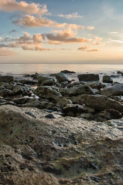 Вертикальний Знімок Пляжу Повного Каменів Спокійним Морем Задньому Плані Ввечері — стокове фото
