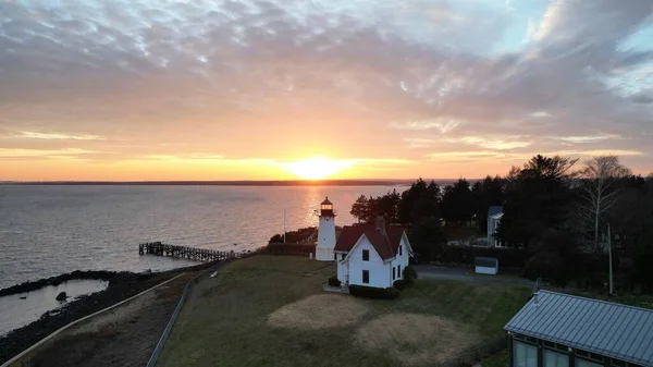 在海面上拍了一帧灿烂的落日 并在海岸上的一座房子旁边建了一座灯塔 — 图库照片