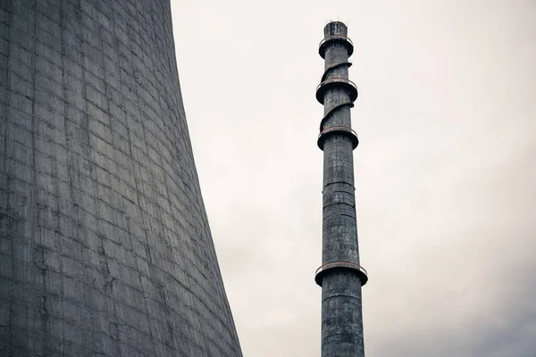 在反应堆冷却塔旁边的烟烟囱的低角度灰度射击 — 图库照片