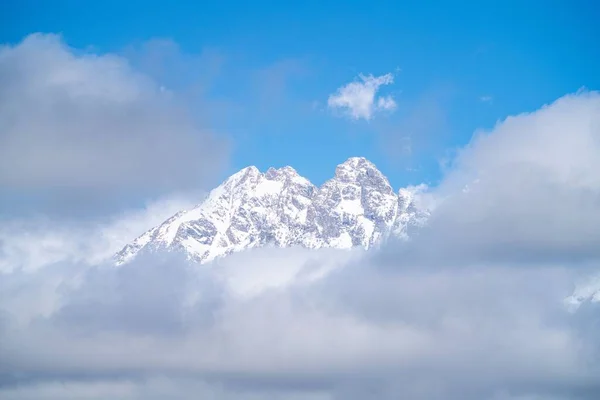 晴れた日には雲に囲まれた雪の山の頂上の豪華な景色 — ストック写真