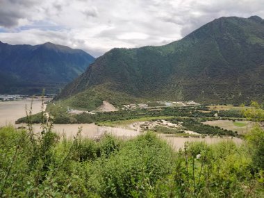 Yeşil kıyı manzarası Göl kenarında yeşil dağlar bulutlu günbatımı gökyüzü altında