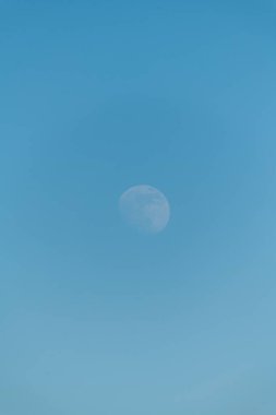 Bulutsuz mavi gökyüzünün gündüz vakti ay ile dikey görüntüsü.