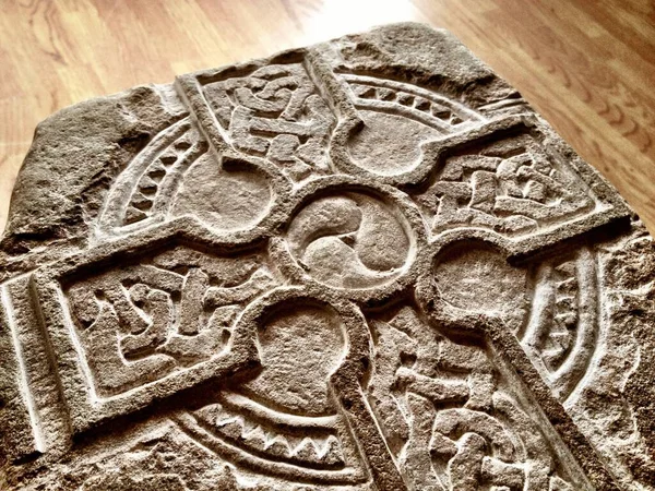木製の地面に石に刻まれたケルトの十字架のクローズアップショット — ストック写真